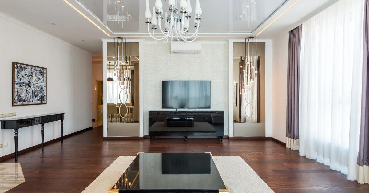 Salon élégant avec lustre, TV et décoration moderne.
